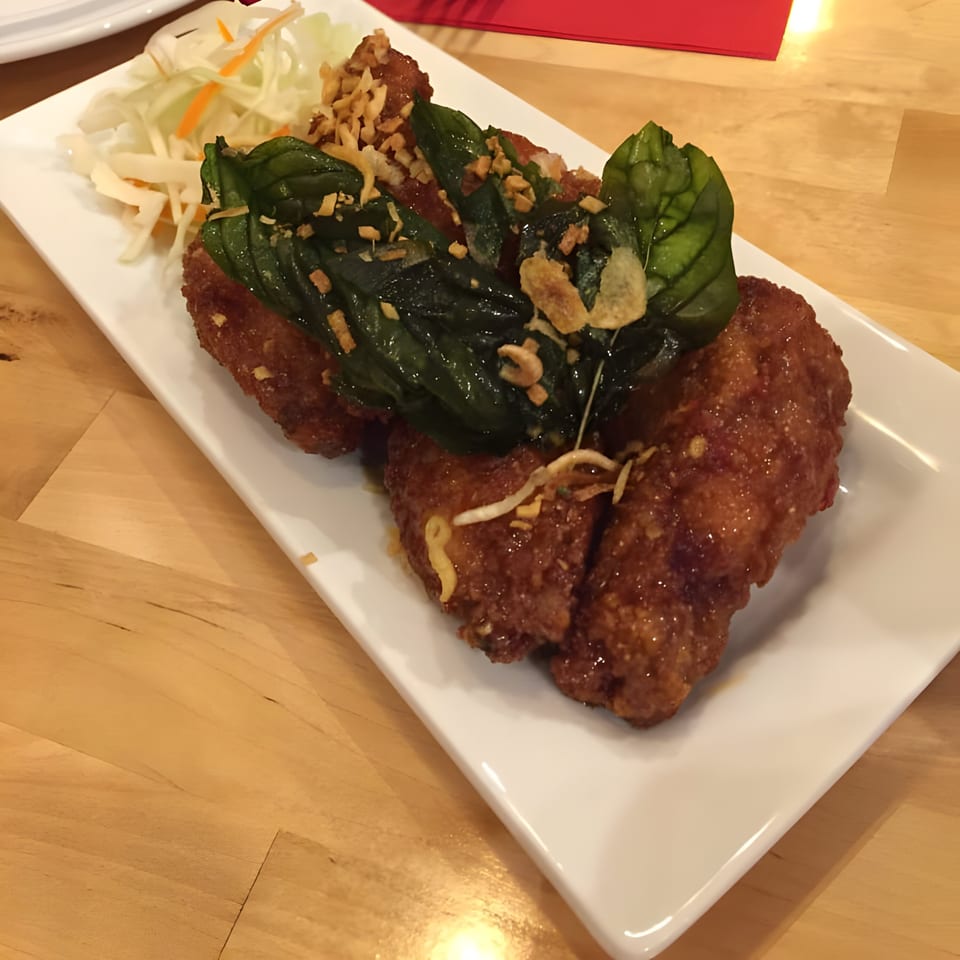 Crispy fried chicken wings with basil and fried garlic, served with shredded cabbage.