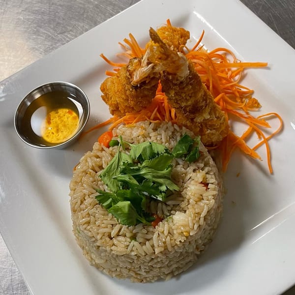 Eat Thai's fried shrimp and rice dish, garnished with shredded carrots, cilantro, and dipping sauce.